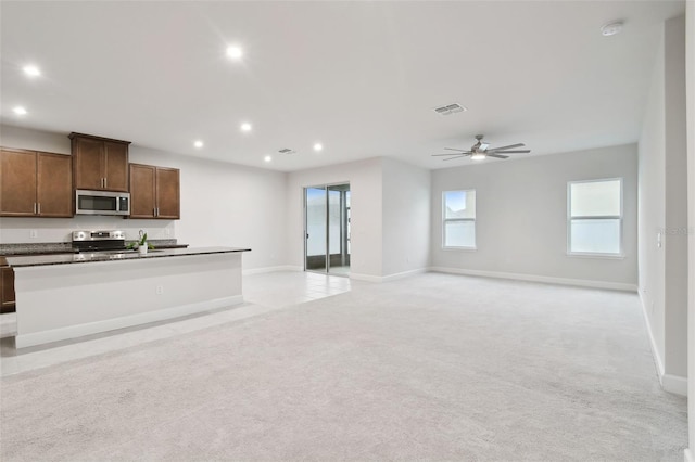 kitchen featuring light carpet, a center island with sink, open floor plan, stainless steel appliances, and recessed lighting