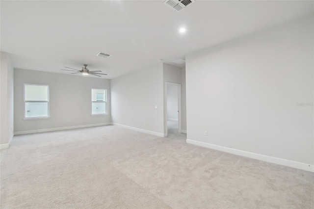 empty room with a ceiling fan, light colored carpet, visible vents, and baseboards