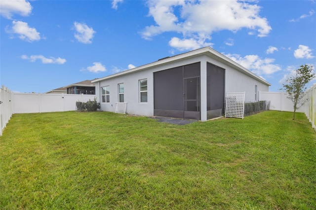 rear view of property featuring a lawn, a fenced backyard, a sunroom, and stucco siding