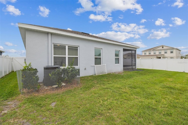 back of property featuring a fenced backyard, central AC, a lawn, and stucco siding