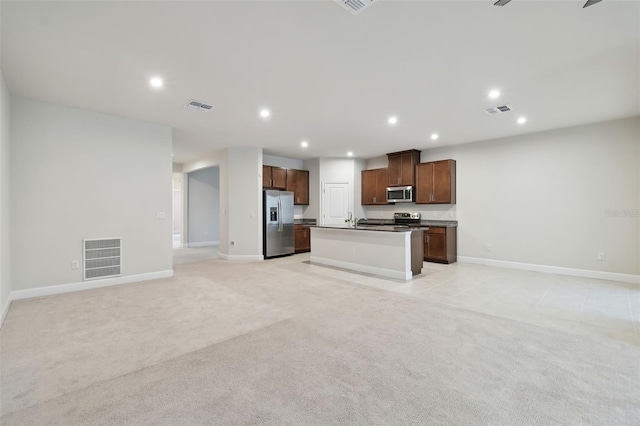 kitchen with dark countertops, light carpet, appliances with stainless steel finishes, and open floor plan