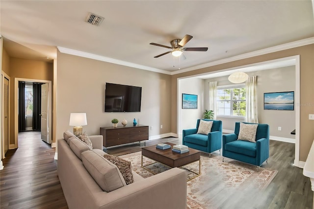 living room with ornamental molding, visible vents, baseboards, and wood finished floors