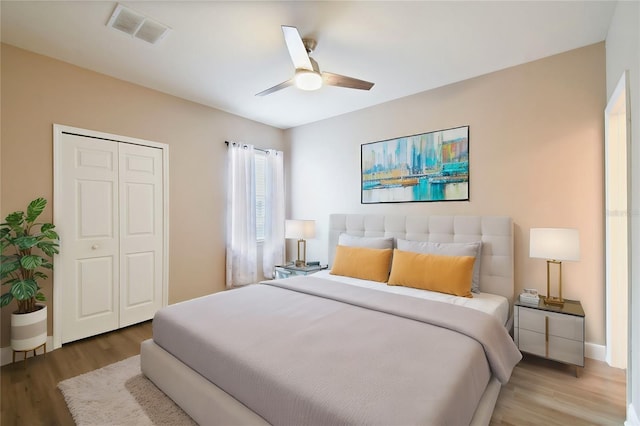 bedroom featuring ceiling fan, a closet, visible vents, and wood finished floors