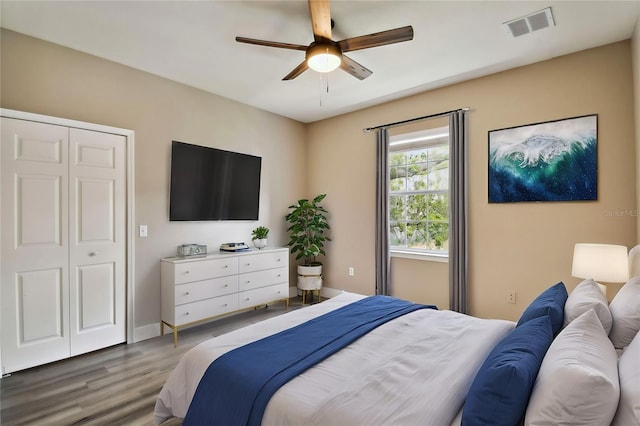 bedroom featuring ceiling fan, wood finished floors, visible vents, and baseboards