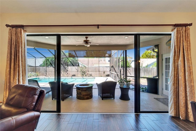 doorway featuring plenty of natural light, wood finished floors, a sunroom, and a ceiling fan