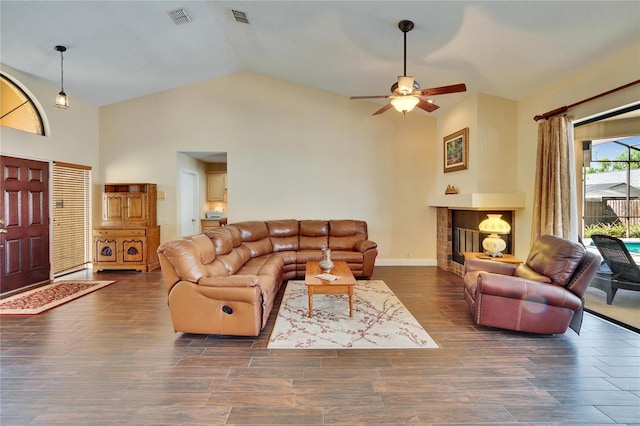 living room featuring high vaulted ceiling, visible vents, wood finished floors, and a glass covered fireplace