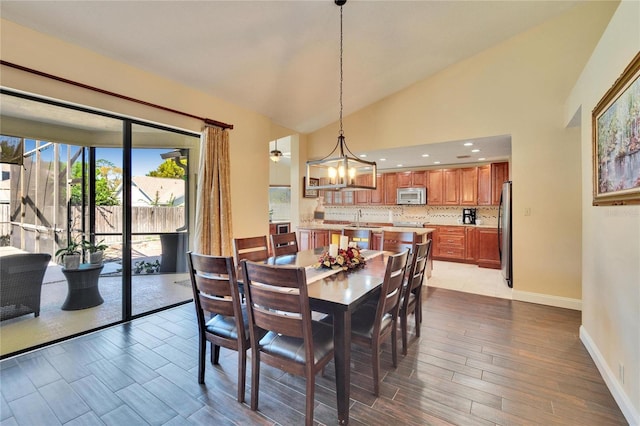 dining space featuring high vaulted ceiling, recessed lighting, wood finished floors, a chandelier, and baseboards