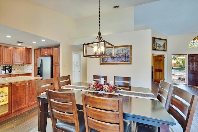 dining area featuring visible vents, dark wood-type flooring, a high ceiling, a notable chandelier, and recessed lighting