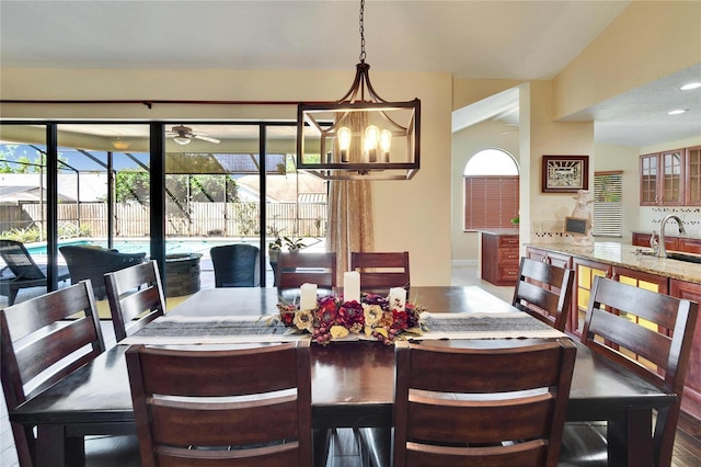 dining space featuring ceiling fan with notable chandelier and a sunroom