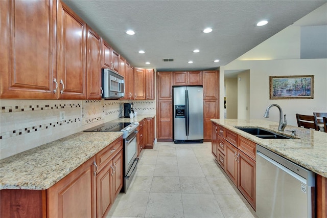 kitchen featuring stainless steel appliances, visible vents, a sink, and light stone counters