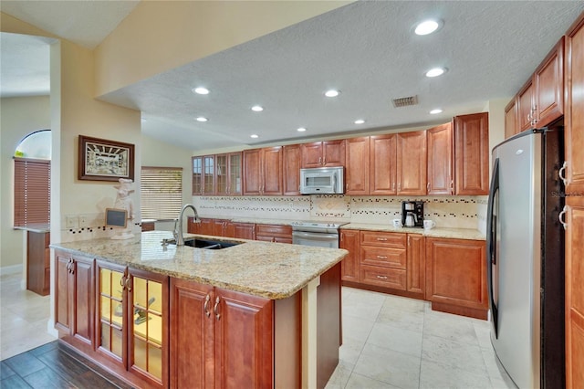 kitchen featuring stainless steel appliances, a sink, visible vents, decorative backsplash, and light stone countertops