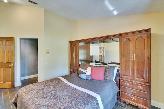 bedroom with lofted ceiling, visible vents, dark wood finished floors, and baseboards