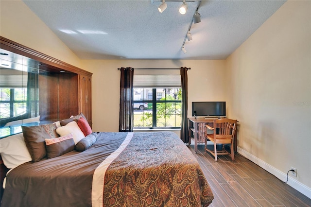 bedroom with wood tiled floor, multiple windows, baseboards, and a textured ceiling