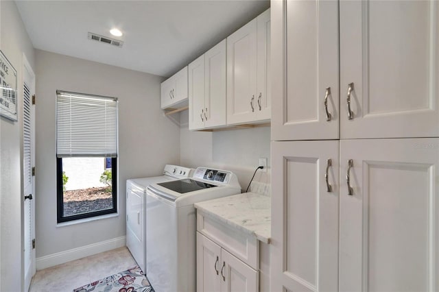 laundry area featuring light tile patterned flooring, visible vents, baseboards, independent washer and dryer, and cabinet space