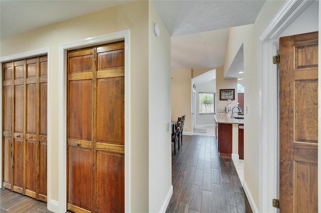 hall with dark wood-style floors and baseboards