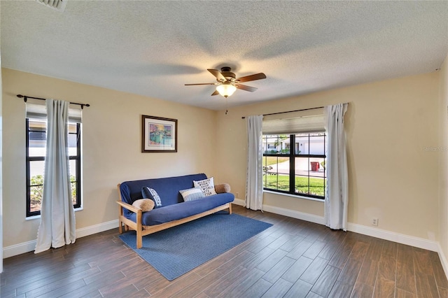 living area with dark wood-style flooring, ceiling fan, a textured ceiling, and baseboards