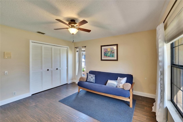 living area featuring baseboards, visible vents, a ceiling fan, wood finished floors, and a textured ceiling