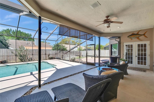 view of swimming pool with glass enclosure, french doors, a patio area, and a fenced backyard