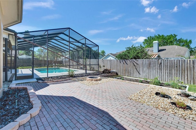 view of patio / terrace with glass enclosure, a fenced backyard, and a fenced in pool