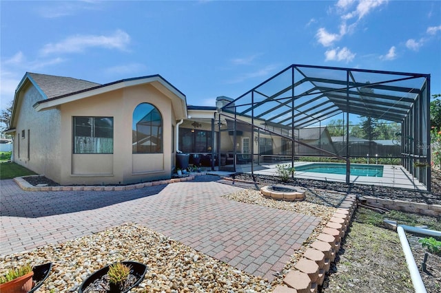 rear view of property with a fenced in pool, a lanai, a patio area, and stucco siding