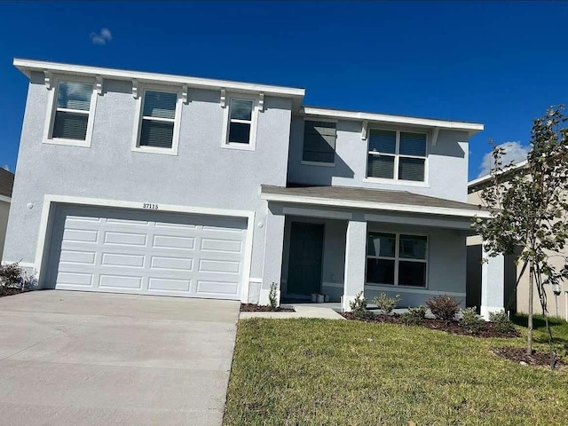 traditional home featuring stucco siding, driveway, a front yard, and a garage