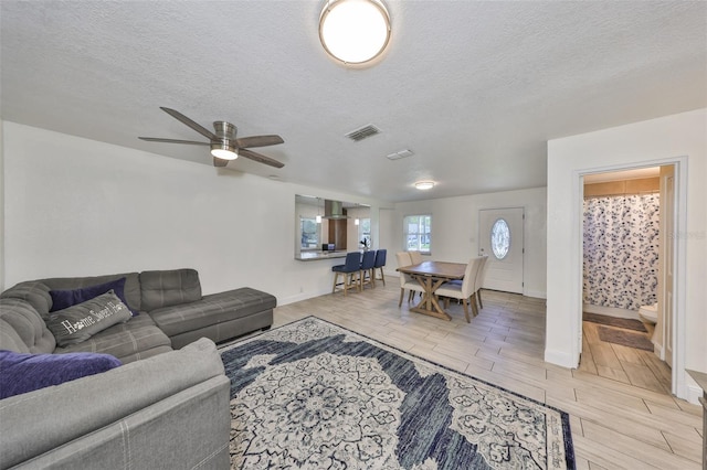 living room featuring a textured ceiling, wood finish floors, visible vents, and baseboards