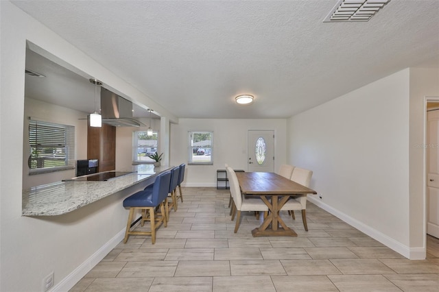 dining space with visible vents, a textured ceiling, and baseboards