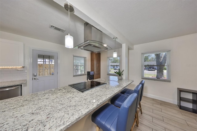 kitchen with black electric stovetop, visible vents, wood tiled floor, light stone countertops, and wall chimney exhaust hood