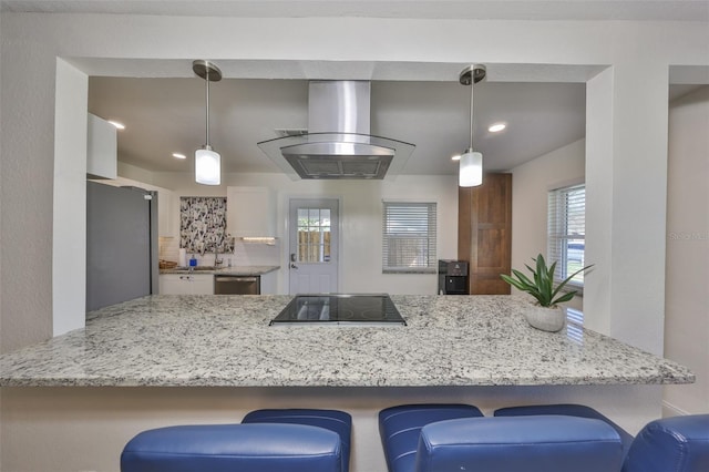 kitchen with island range hood, stainless steel appliances, backsplash, light stone countertops, and pendant lighting