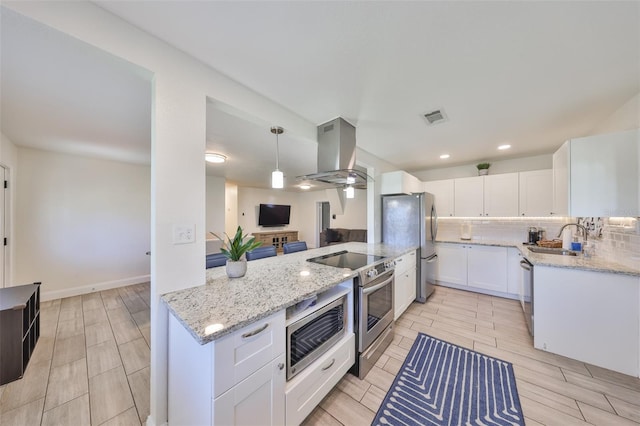 kitchen featuring visible vents, decorative backsplash, island exhaust hood, stainless steel appliances, and a sink