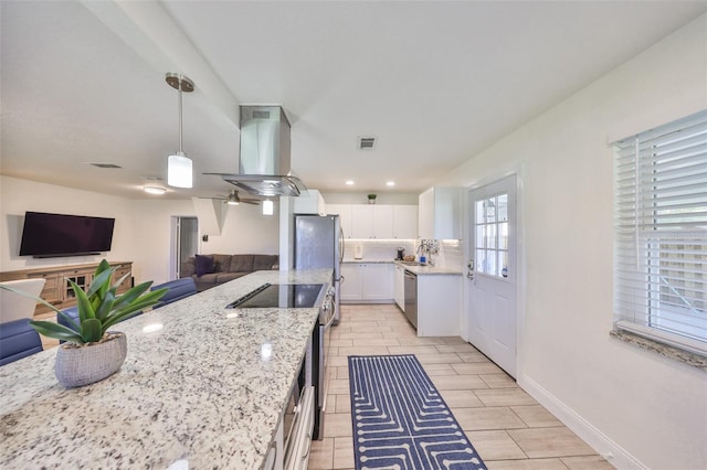 kitchen with visible vents, appliances with stainless steel finishes, white cabinetry, island range hood, and light stone countertops