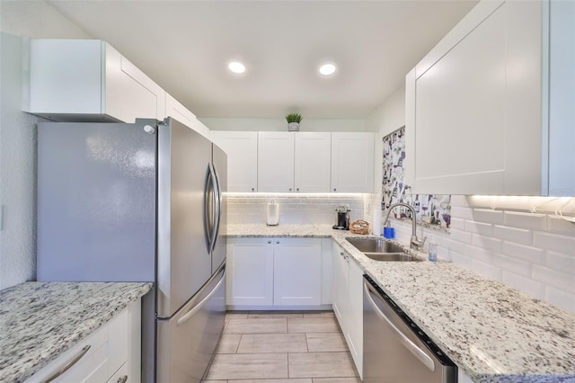 kitchen with appliances with stainless steel finishes, backsplash, a sink, and white cabinets