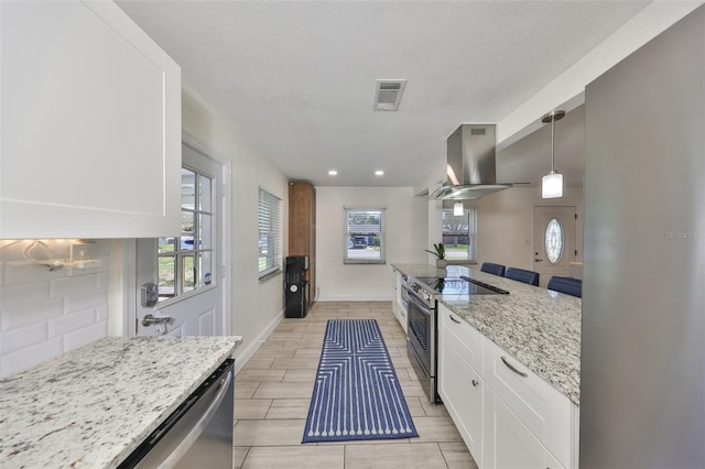 kitchen with light stone counters, stainless steel appliances, visible vents, white cabinetry, and island range hood