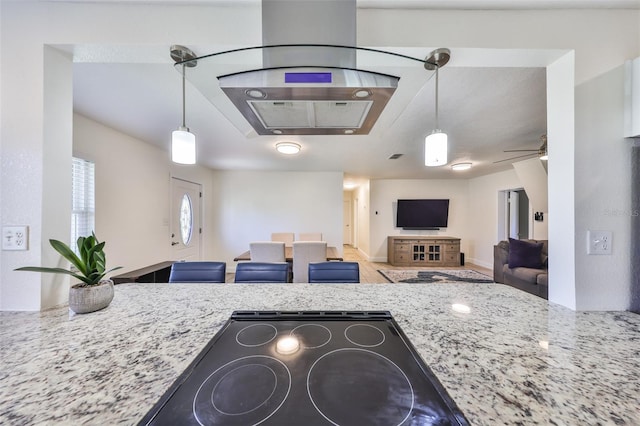 kitchen featuring ceiling fan, light stone counters, open floor plan, and decorative light fixtures