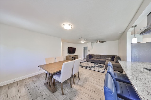 dining room with wood finish floors, a ceiling fan, and baseboards