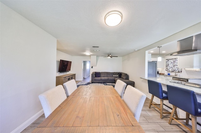 dining space featuring baseboards, visible vents, a ceiling fan, and a textured ceiling