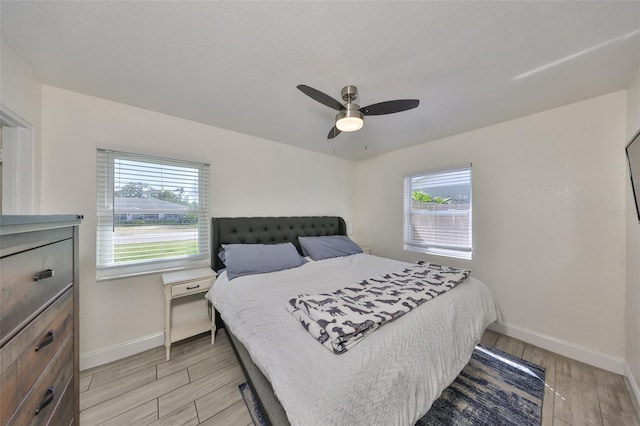 bedroom featuring light wood-style floors, multiple windows, and baseboards