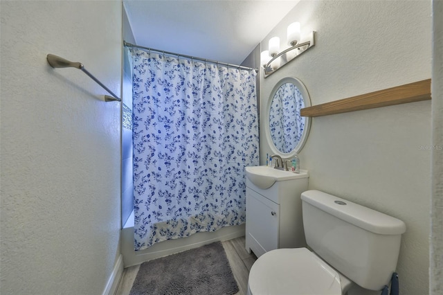 bathroom with toilet, a textured wall, shower / tub combo with curtain, and vanity