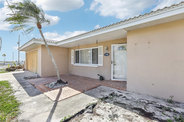 doorway to property featuring a tile roof, a patio area, and brick siding