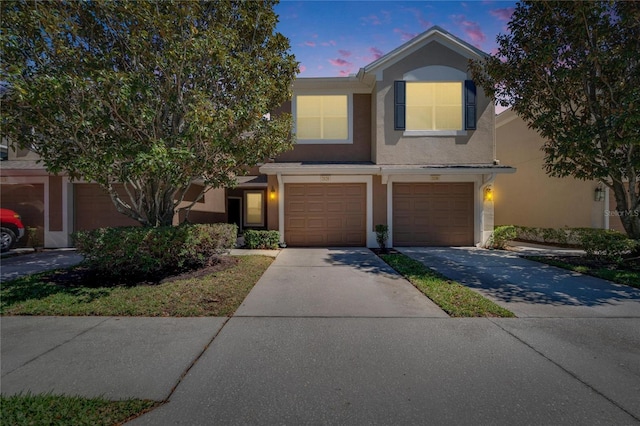 view of front of property with a garage, concrete driveway, and stucco siding