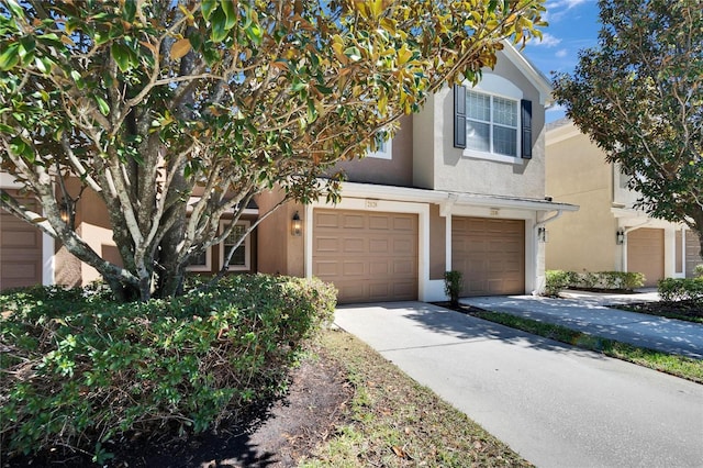 view of front facade with a garage, concrete driveway, and stucco siding