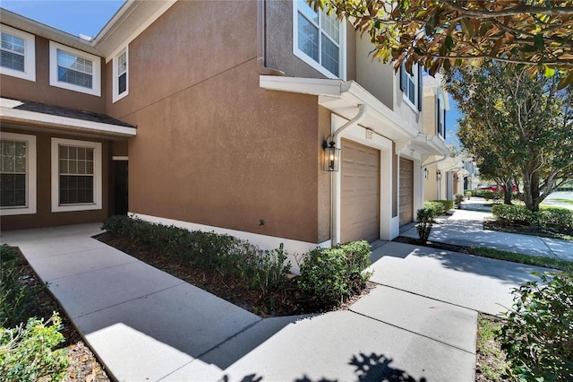 view of home's exterior featuring concrete driveway, an attached garage, and stucco siding