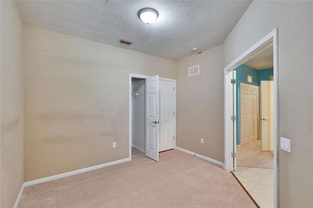 unfurnished bedroom with baseboards, visible vents, light carpet, and a textured ceiling