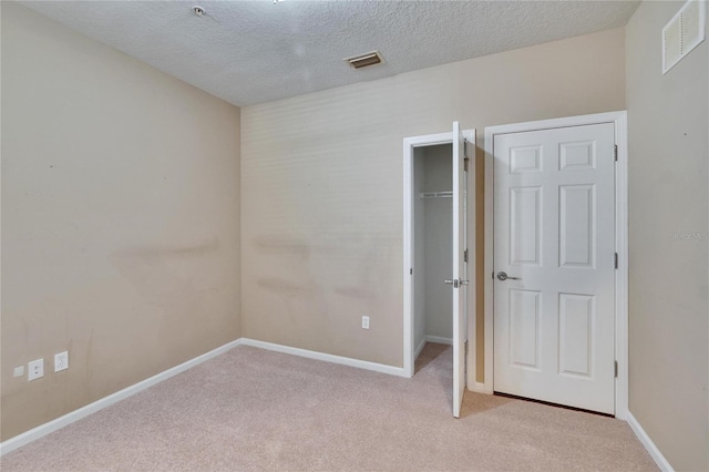 unfurnished bedroom featuring baseboards, visible vents, and light colored carpet