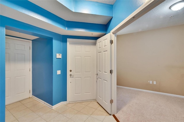 foyer with light carpet, baseboards, and light tile patterned floors