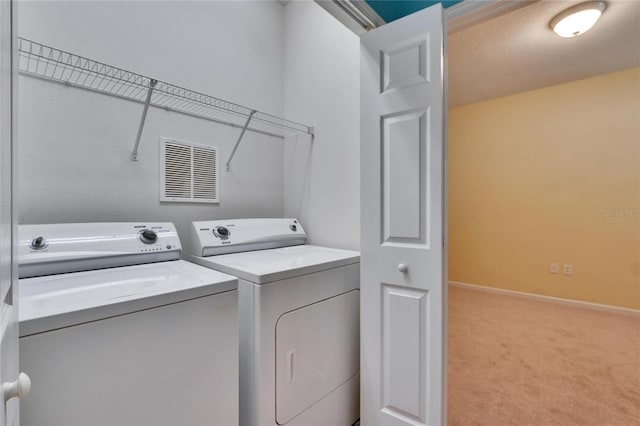 clothes washing area featuring laundry area, visible vents, baseboards, carpet, and washing machine and dryer