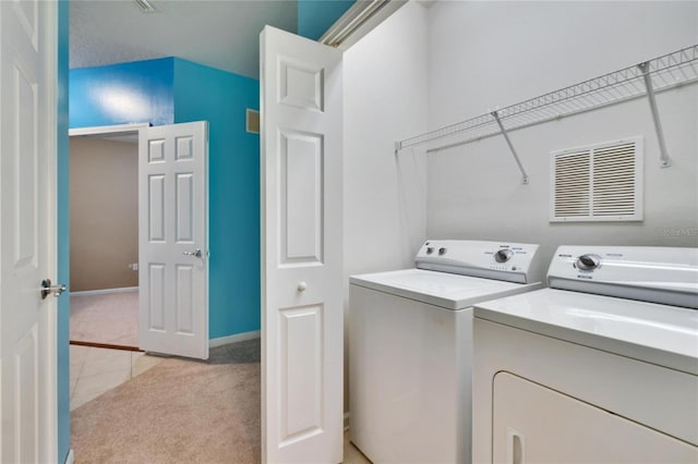 clothes washing area featuring laundry area, washer and clothes dryer, visible vents, and light colored carpet