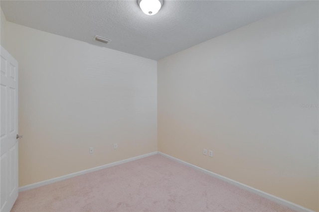 spare room with light carpet, a textured ceiling, visible vents, and baseboards