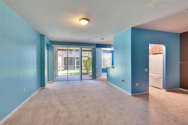 empty room featuring carpet flooring, visible vents, baseboards, and a textured ceiling