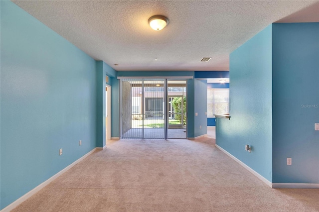 carpeted empty room with visible vents, a textured ceiling, and baseboards